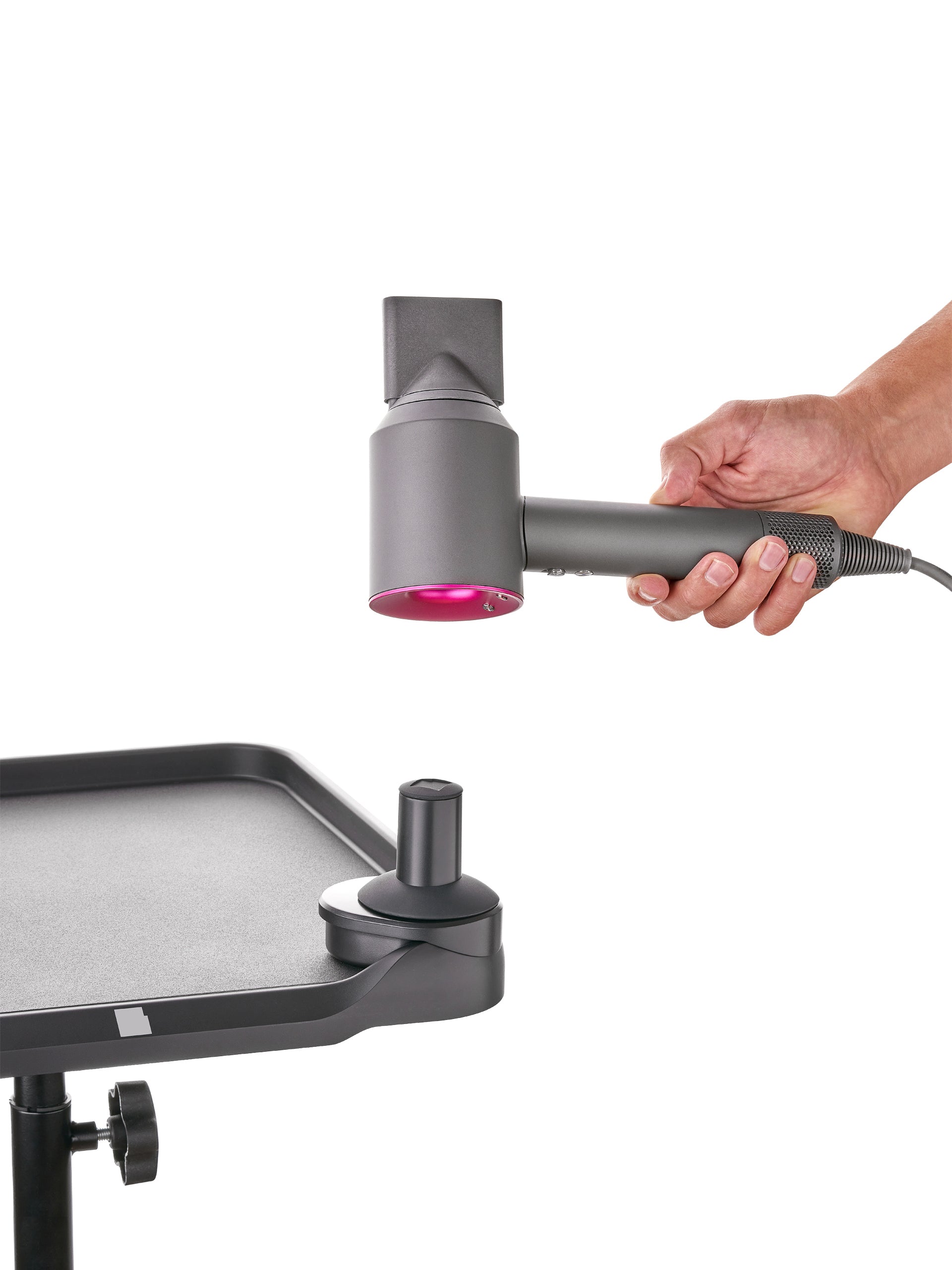 Dyson hair dryer resting in magnetic holder on LEVSHA rolling color workstation table, keeping tools secure for balayage and foilyage services